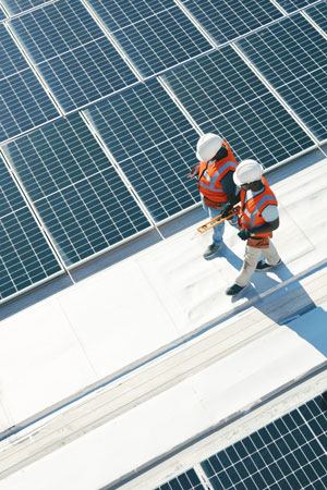 technicians walking on commercial building roof planning for inspection of solar panels