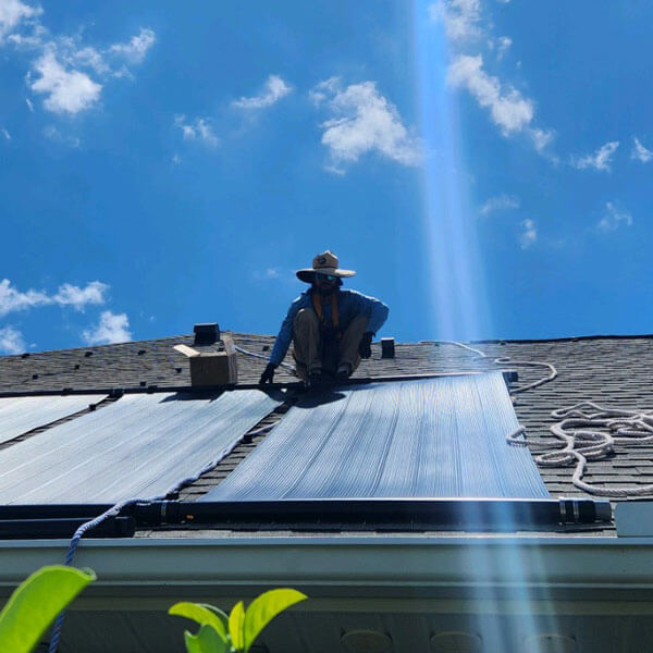 Technician installing pool solar panels on residential roof